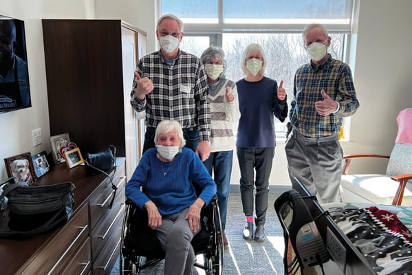 Residents and staff giving thumbs up in a bright room
