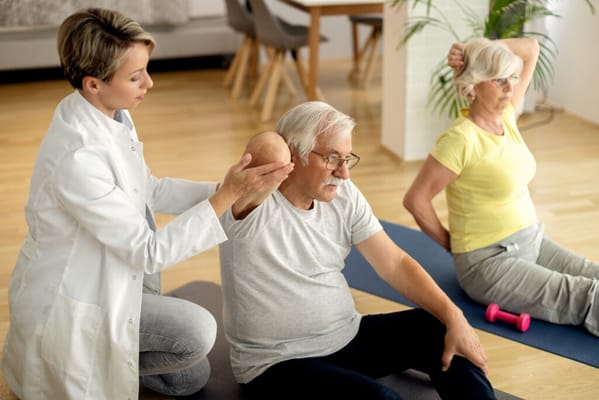 Therapist assisting elderly man in exercise session