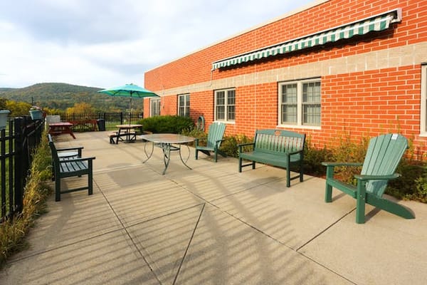 Outdoor patio area with green benches and tables