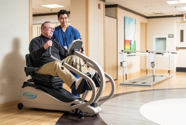Resident using therapy equipment with staff assistance