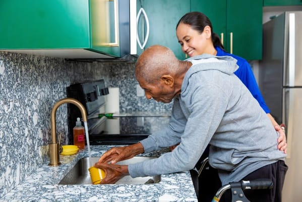 Staff helping a resident with dishes in the kitchen