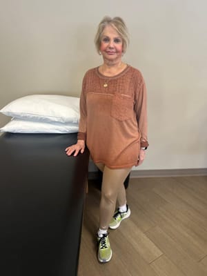 A smiling woman in activewear standing inside a facility
