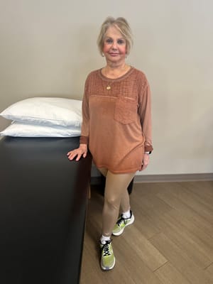 A smiling woman in activewear standing inside a facility