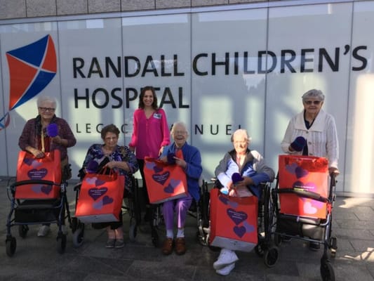 Residents smiling with gifts in front of a hospital