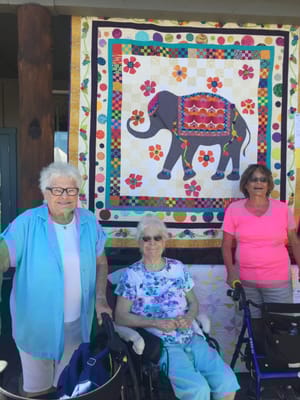 Residents posing in front of a colorful quilt display