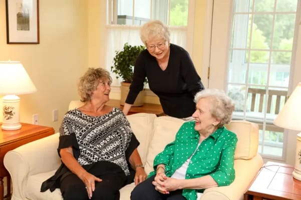 Three residents enjoying conversation in a cozy living area