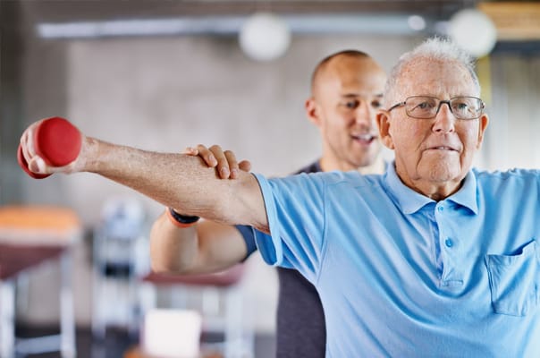 Senior man exercising with a fitness trainer indoors
