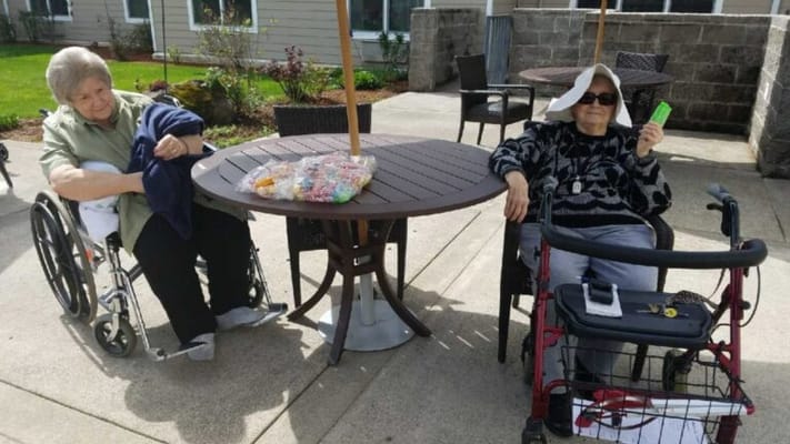 Two elderly women sitting outside at a table