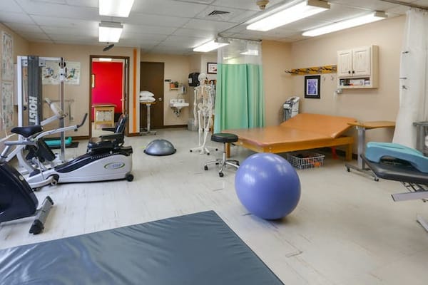 A physical therapy room with exercise equipment and mats