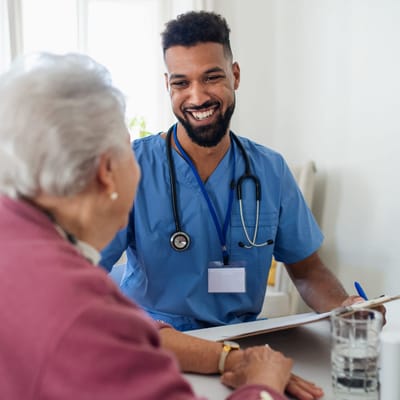 A caregiver smiling with an elderly resident indoors