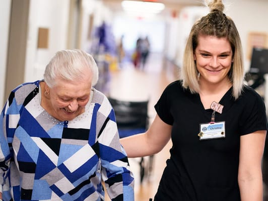 A staff member assisting a resident in a hallway