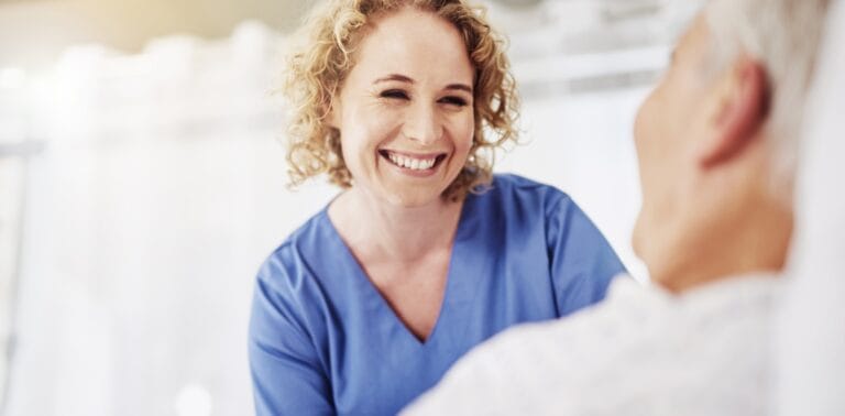 A caregiver smiling with a resident in a bright room