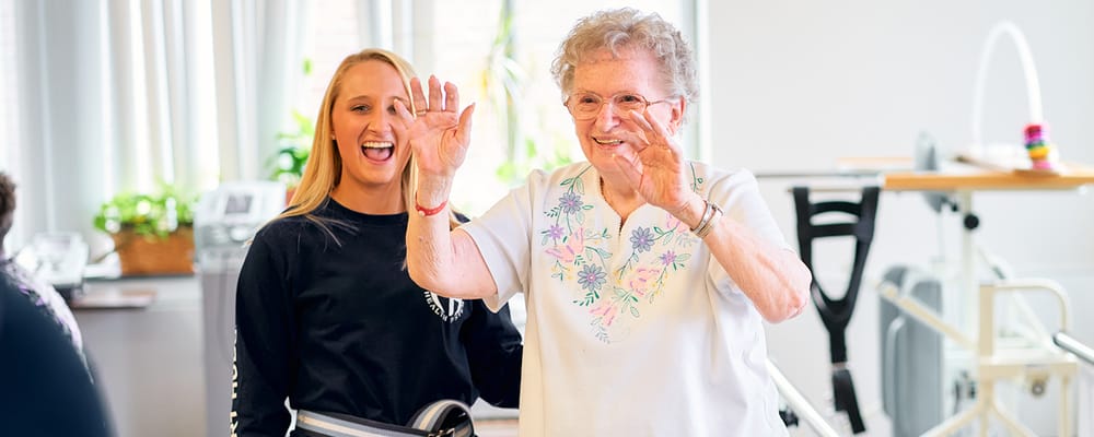 Resident interacting cheerfully with staff in an activity room