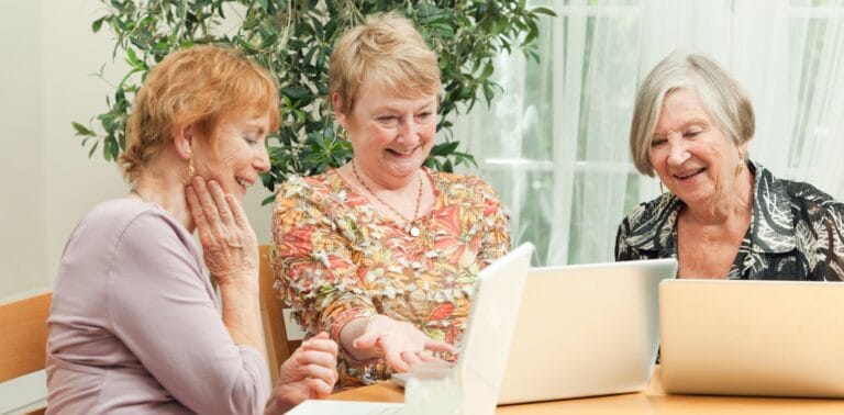 Three residents engaging around a laptop in a bright room