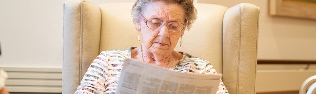 Senior woman reading a newspaper in a comfortable chair