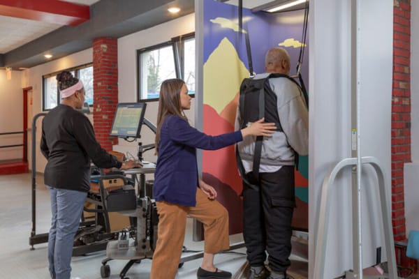 Staff assisting a resident with rehabilitation equipment