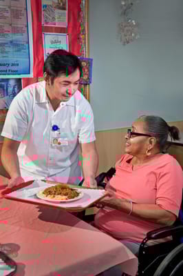 Staff member serving food to a resident in the dining area