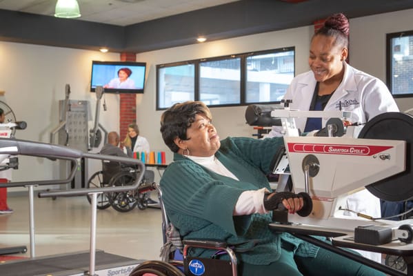Instructor assisting a resident with rehabilitation equipment