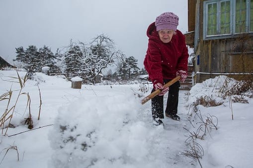 Senior woman shoveling snow in winter