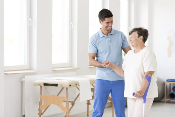 Therapist assisting a smiling senior woman in a bright room