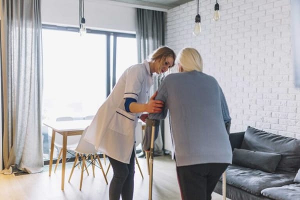 A caregiver assisting a resident in a bright room