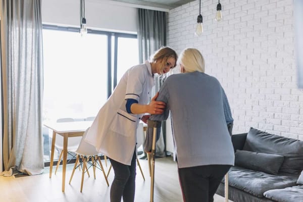 A caregiver assisting a resident in a bright room