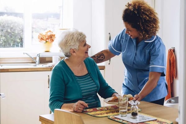 Staff serving food to a resident in a kitchen