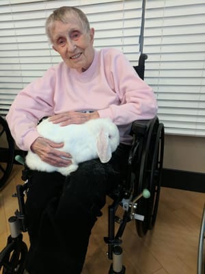 Resident smiling with a rabbit in her lap