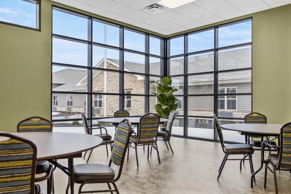 Bright common area with tables and chairs overlooking a garden
