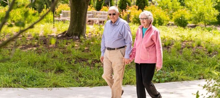 Two seniors walking hand in hand in a garden