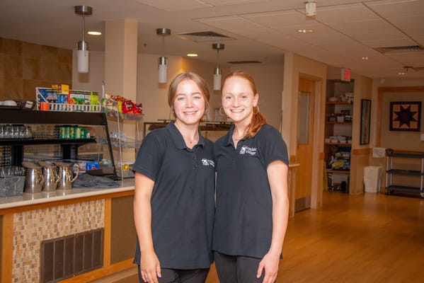 Two staff members smiling in a common area