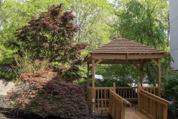 Wooden gazebo surrounded by colorful shrubs