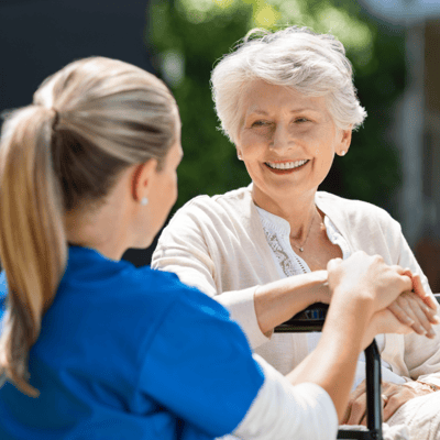 A caregiver interacting warmly with a senior resident in an outdoor space