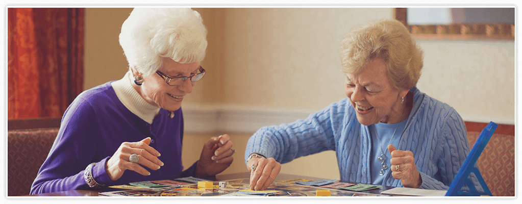 Two senior women playing a board game in a cozy room
