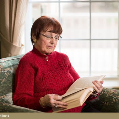 Senior woman reading a book in a cozy chair
