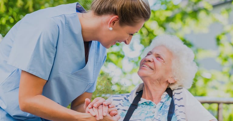 Caregiver interacting warmly with a senior resident outdoors