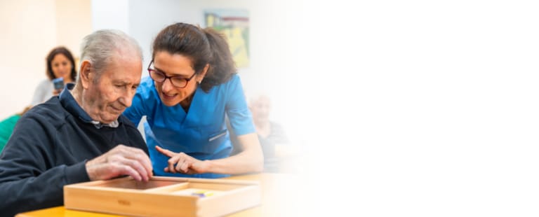 Staff assisting a resident with an activity in a common area