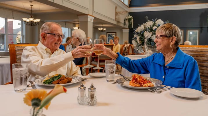Residents enjoying a meal and toasting in the dining room