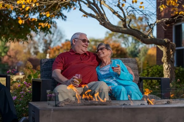 Elderly couple enjoying drinks by an outdoor fire pit