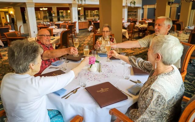Residents toasting with drinks at a dining table