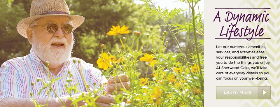 An elderly man smiling in a flower garden