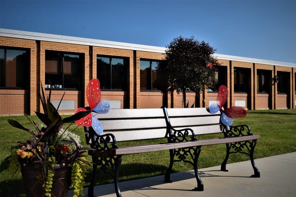 Outdoor bench with butterfly decorations in front of a building