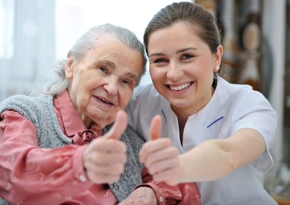 An elderly resident and caregiver giving thumbs up