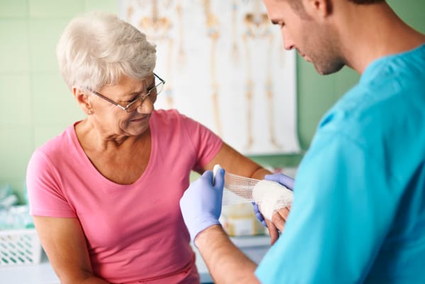 Healthcare professional assisting a senior with wound care