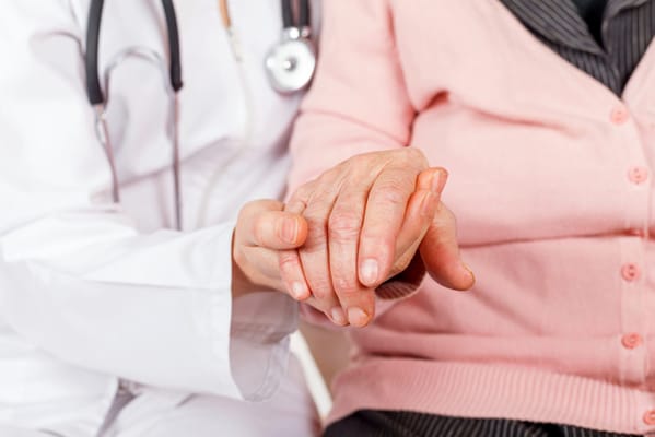 A caregiver holding a senior's hand in a supportive gesture