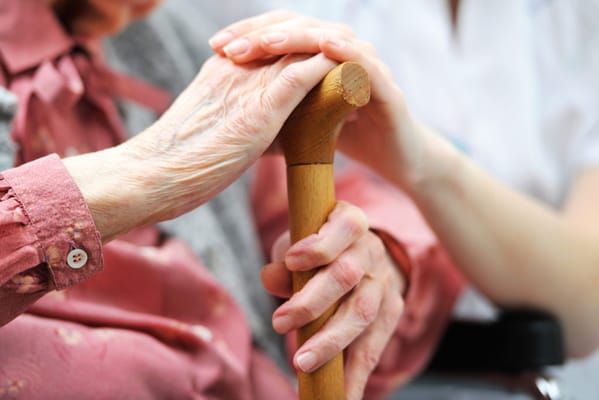 Close-up of hands resting on a cane