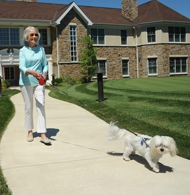 Resident walking a small dog along the pathway