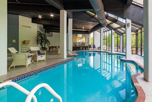 Indoor swimming pool area with lounge chairs and large windows
