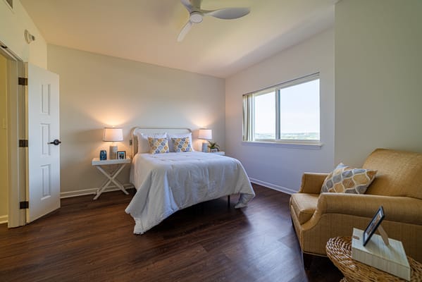 A bright private resident room with a bed and seating area