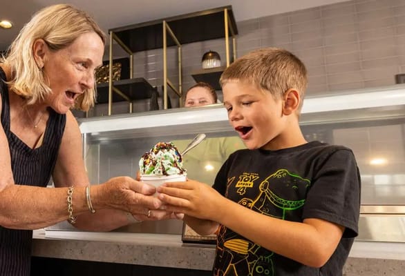 A woman serving ice cream to a child indoors